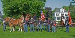 group of people in old fashioned military uniforms with a horse